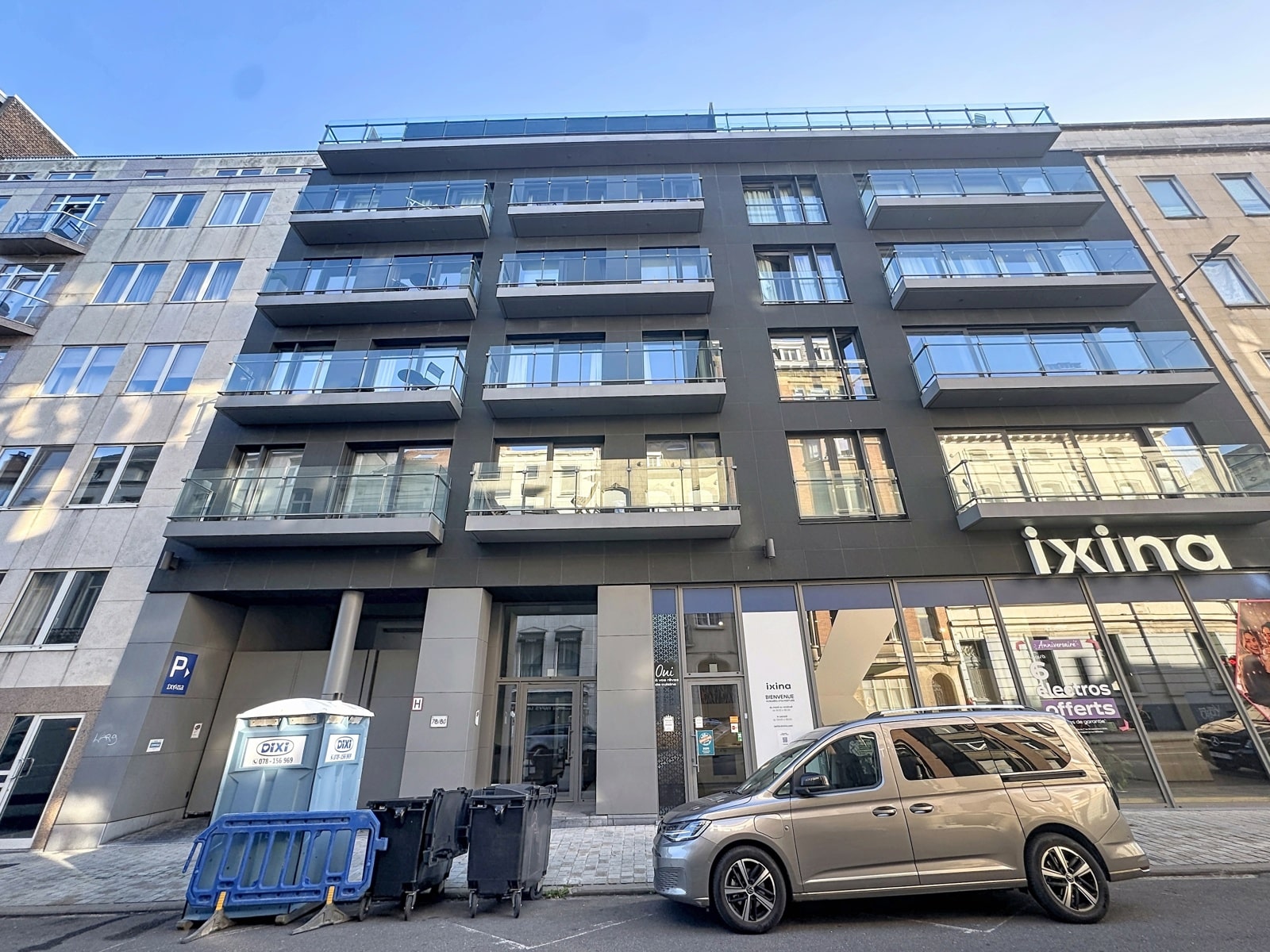 Modern Facade with Balconies – You Real Estate Agency A modern building with apartments and balconies, and a store on the ground floor.
