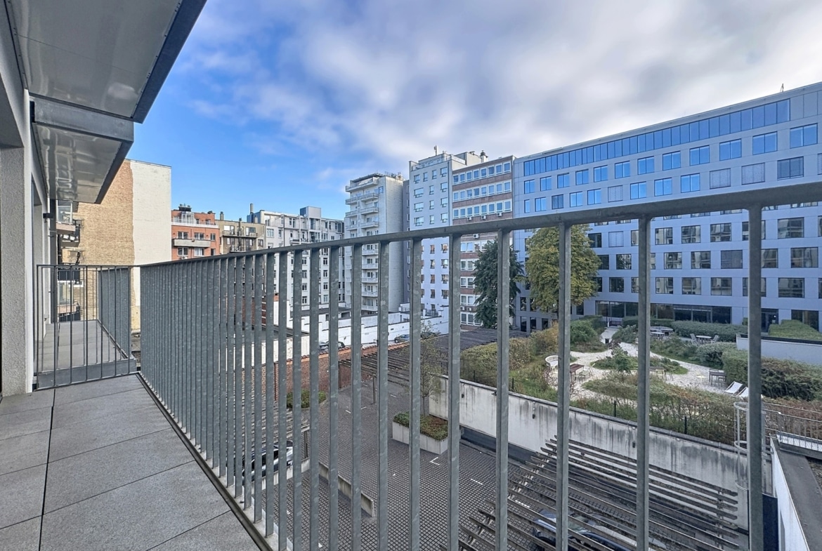 Modern apartment terrace with a view of an inner courtyard and city buildings.