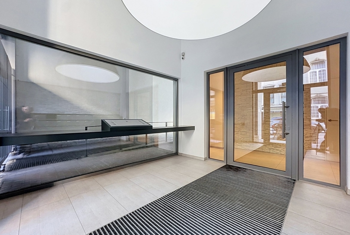 Modern building lobby with glass doors and light-colored tile flooring.