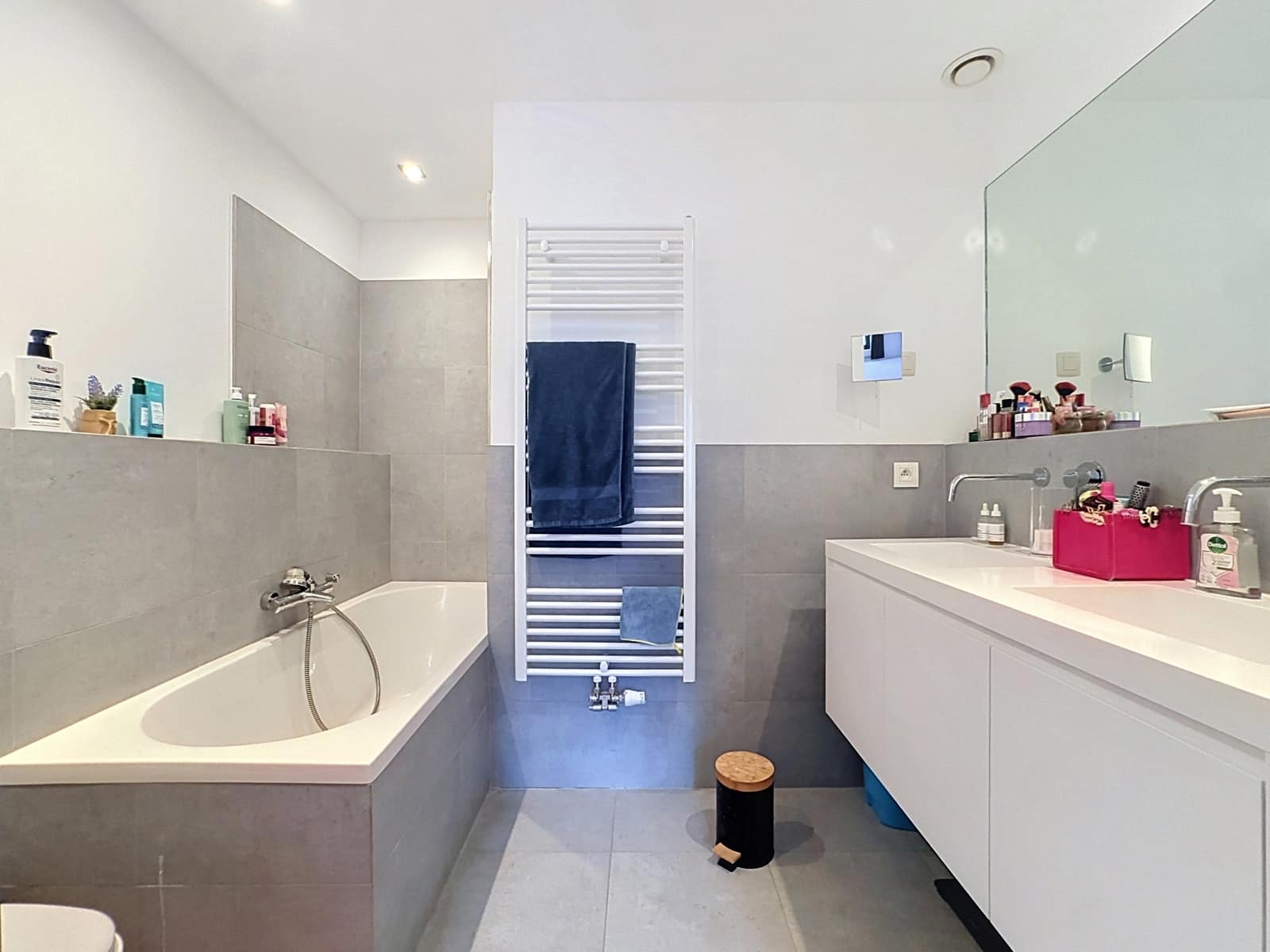 Modern bathroom with bath - You Real Estate Agency Modern apartment bathroom with a bathtub, wall-mounted sink, and large mirror.
