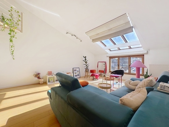 Salon lumineux dappartement sous combles avec canapé bleu et fenêtres de toit   appartement 2 chambres  ixelles