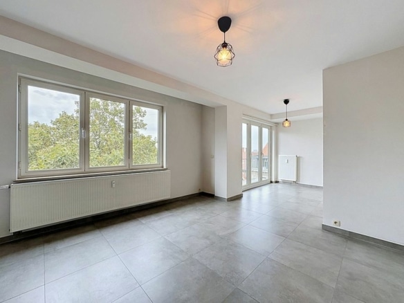 Salon lumineux dappartement moderne vide avec grandes fenêtres et radiateurs   appartement 1 chambre  saint gilles