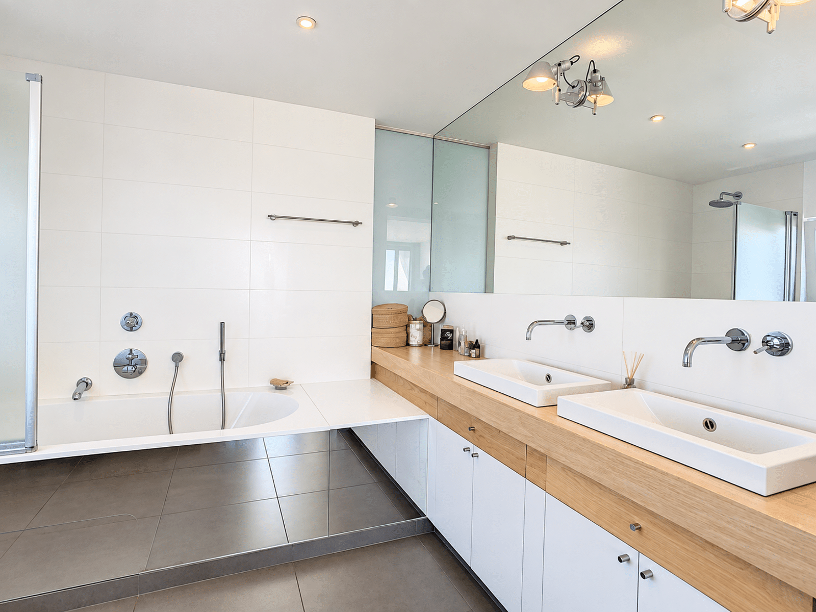Salle de Bain Moderne - You Real Estate Agency Modern bathroom with a bathtub, double sinks, and a glass-enclosed shower in an apartment.