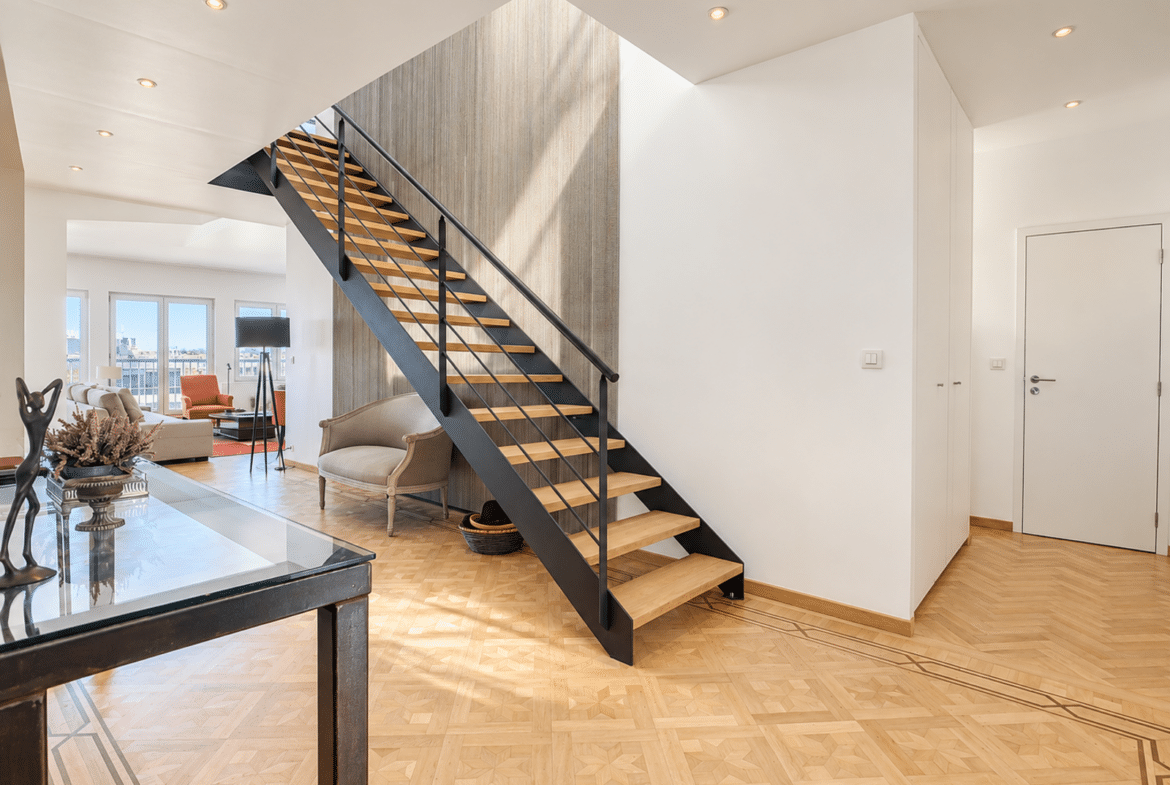 Contemporary home with a stylish staircase, geometric hardwood floors, and a bright living room.