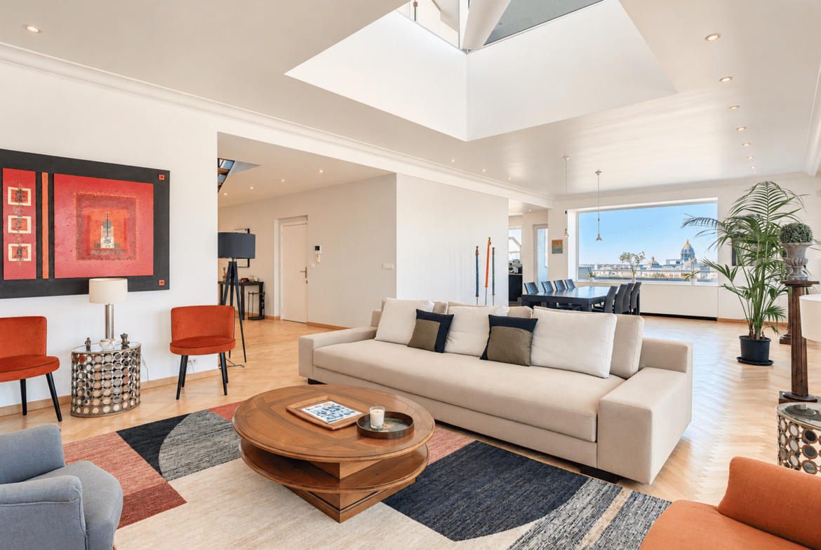Bright living room in a contemporary apartment with a skylight, hardwood floors, and a city view.