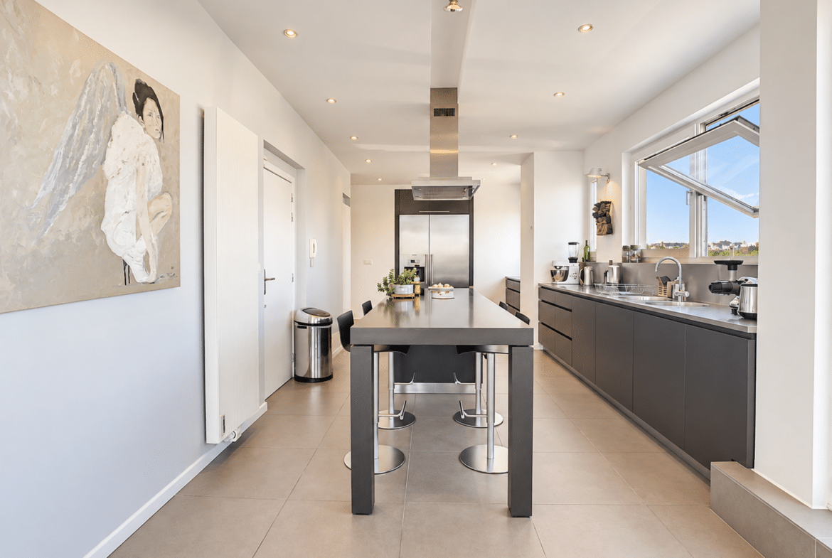 A bright, modern kitchen with a central island and built-in appliances in an apartment.