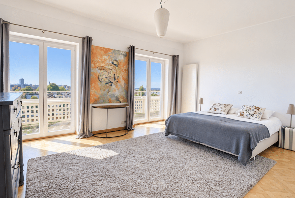 A bright apartment bedroom with a balcony, hardwood floors, and modern decor.