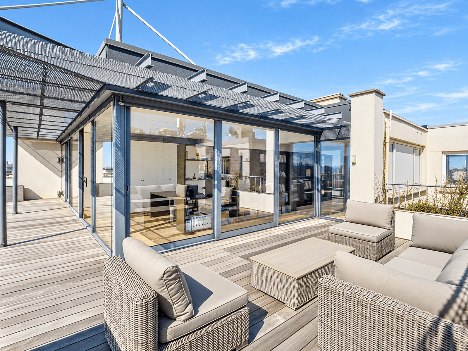 Rooftop Terrace with Outdoor Lounge – You Real Estate Agency Rooftop terrace of a modern apartment with an outdoor living area and floor-to-ceiling windows.