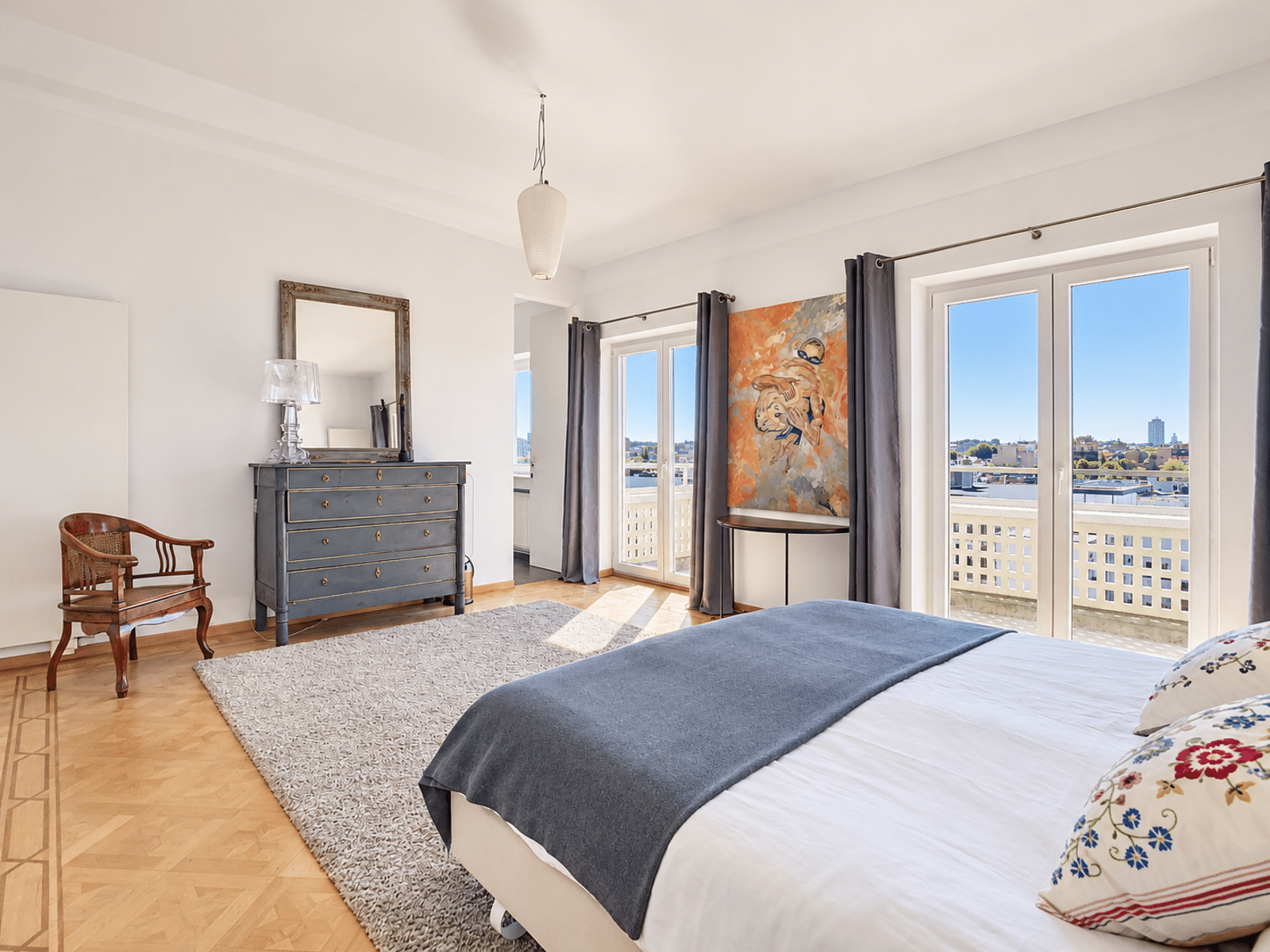 Bright Room with Balcony – You Real Estate Agency A bright apartment room with hardwood floors, a balcony, and a city view.
