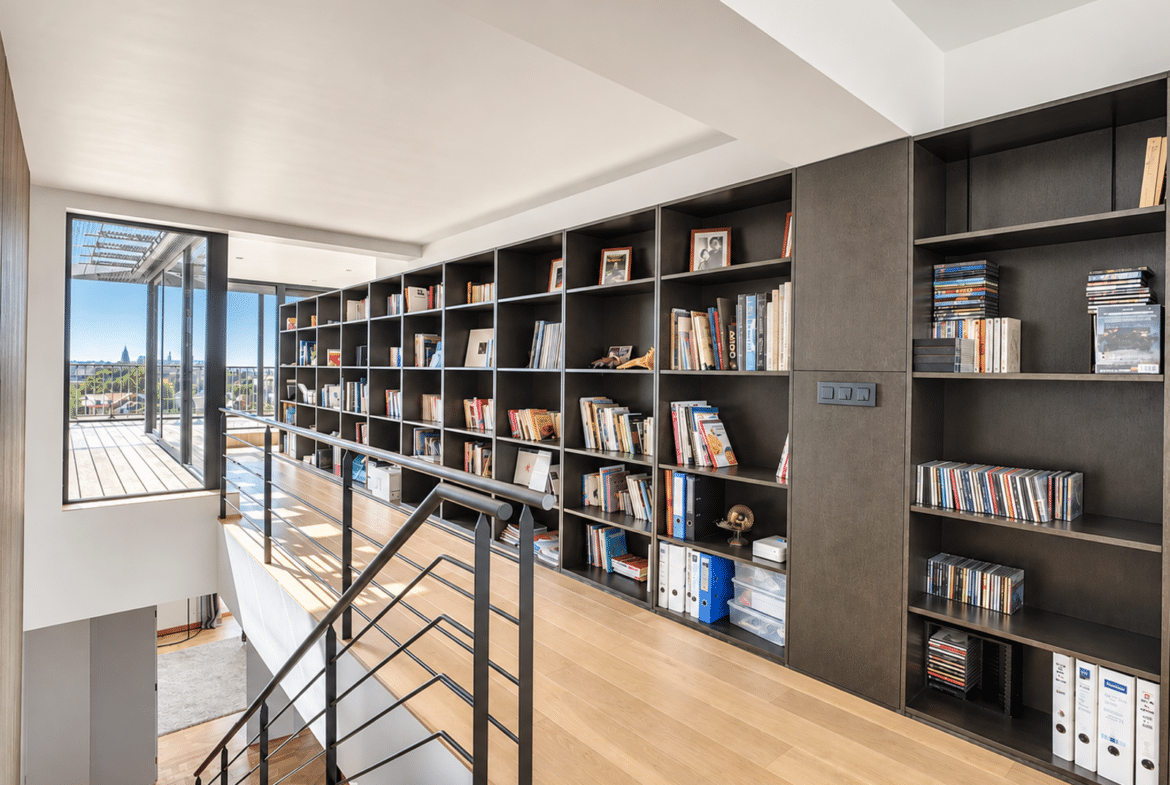 A bright landing with a built-in bookshelf and a terrace in a contemporary home.