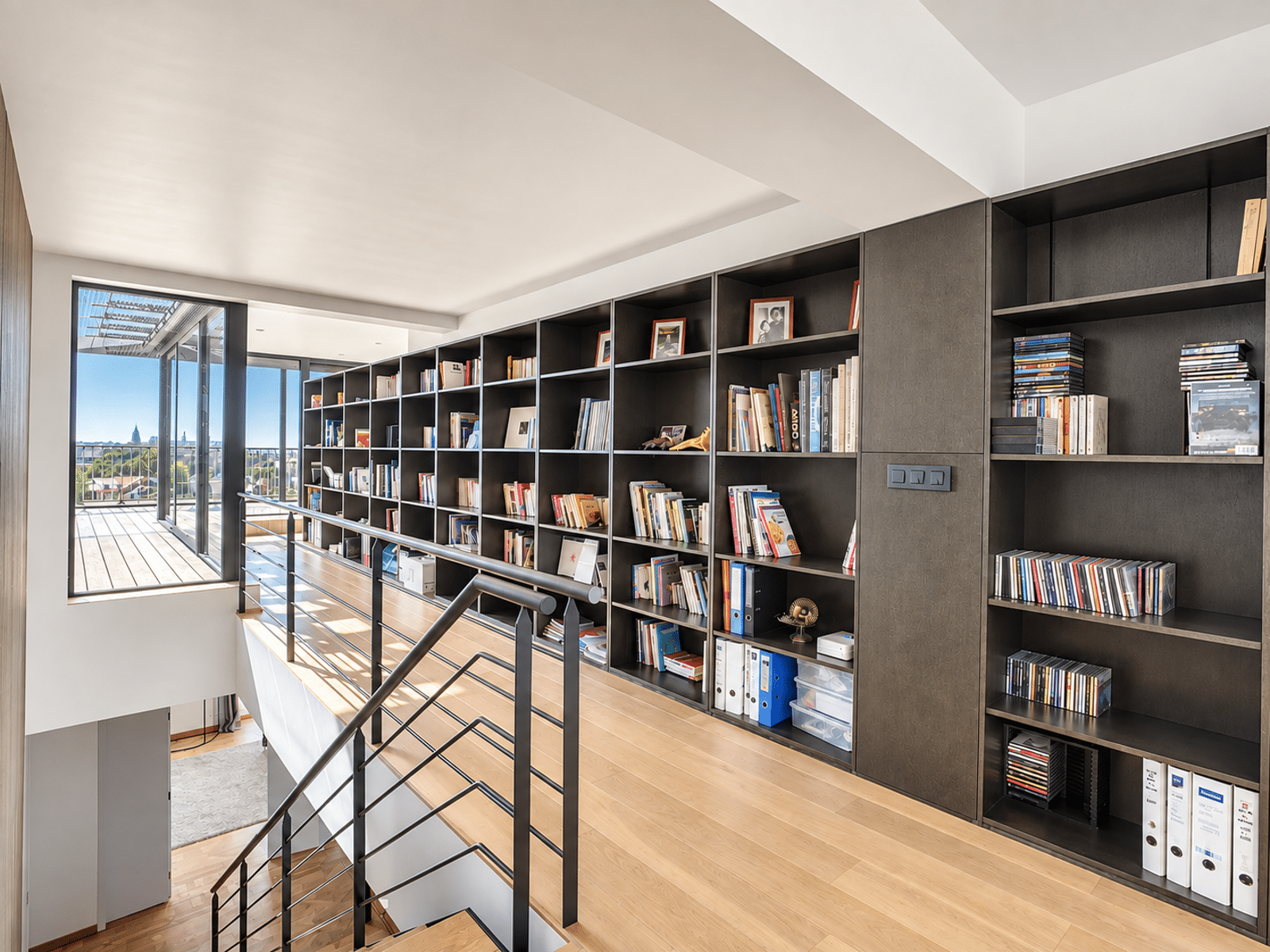Floor with Library and Terrace – You Real Estate Agency A bright landing with a built-in bookshelf and a terrace in a contemporary home.