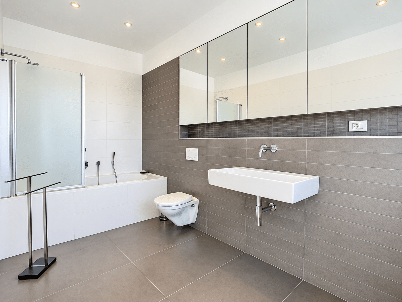 Modern bathroom with bath - You Real Estate Agency Modern bathroom with a bathtub, glass-enclosed shower, and wall-mounted sink in an apartment.
