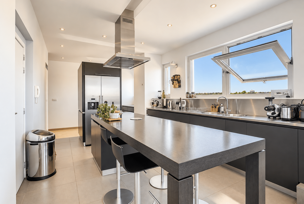 Bright, modern kitchen with a central island and stainless steel appliances in an apartment.