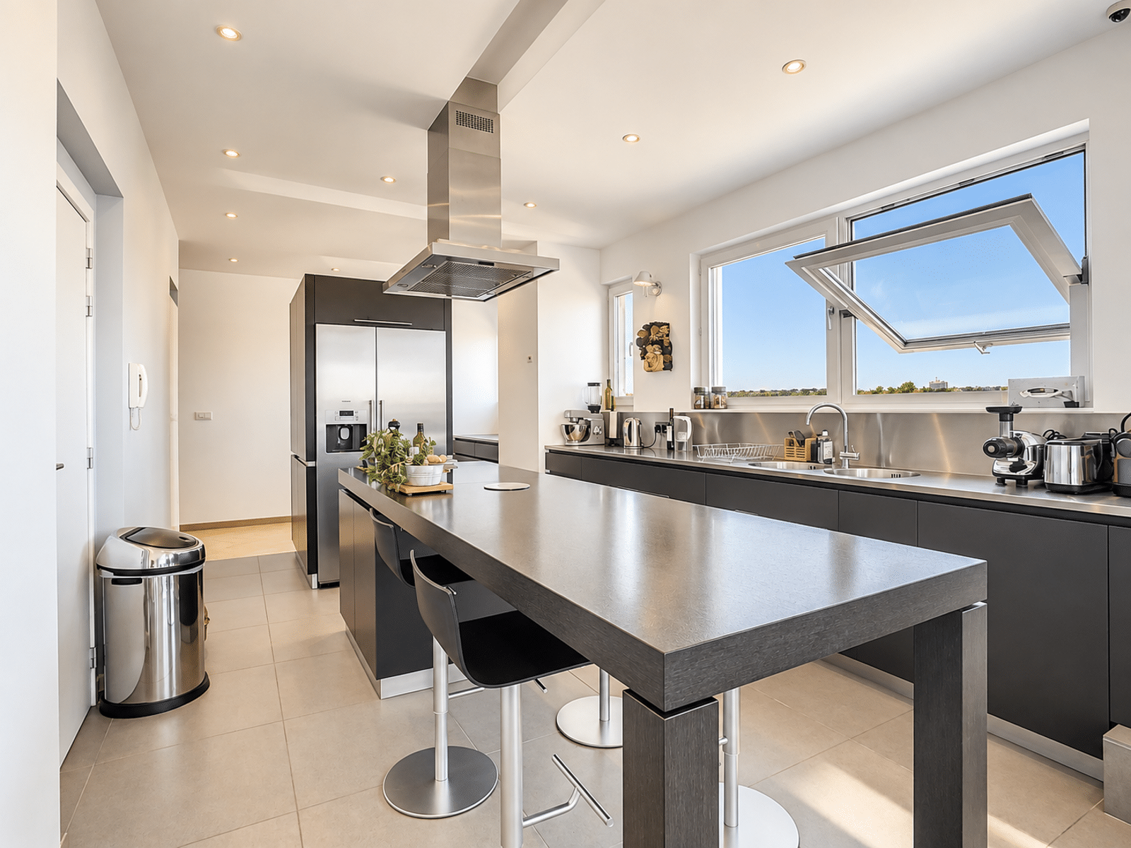 Bright, Modern Kitchen with an Island – You Real Estate Agency Bright, modern kitchen with a central island and stainless steel appliances in an apartment.