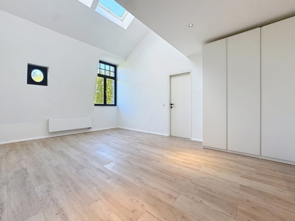 Pièce lumineuse sous combles avec parquet fenêtre et rangements intégrés dans appartement rénové   appartement 1 chambre  brussels