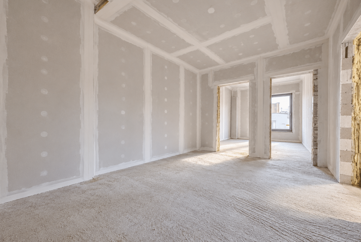 Woonkamer in een appartement in renovatie, met gipsplaatwanden en natuurlijk licht.