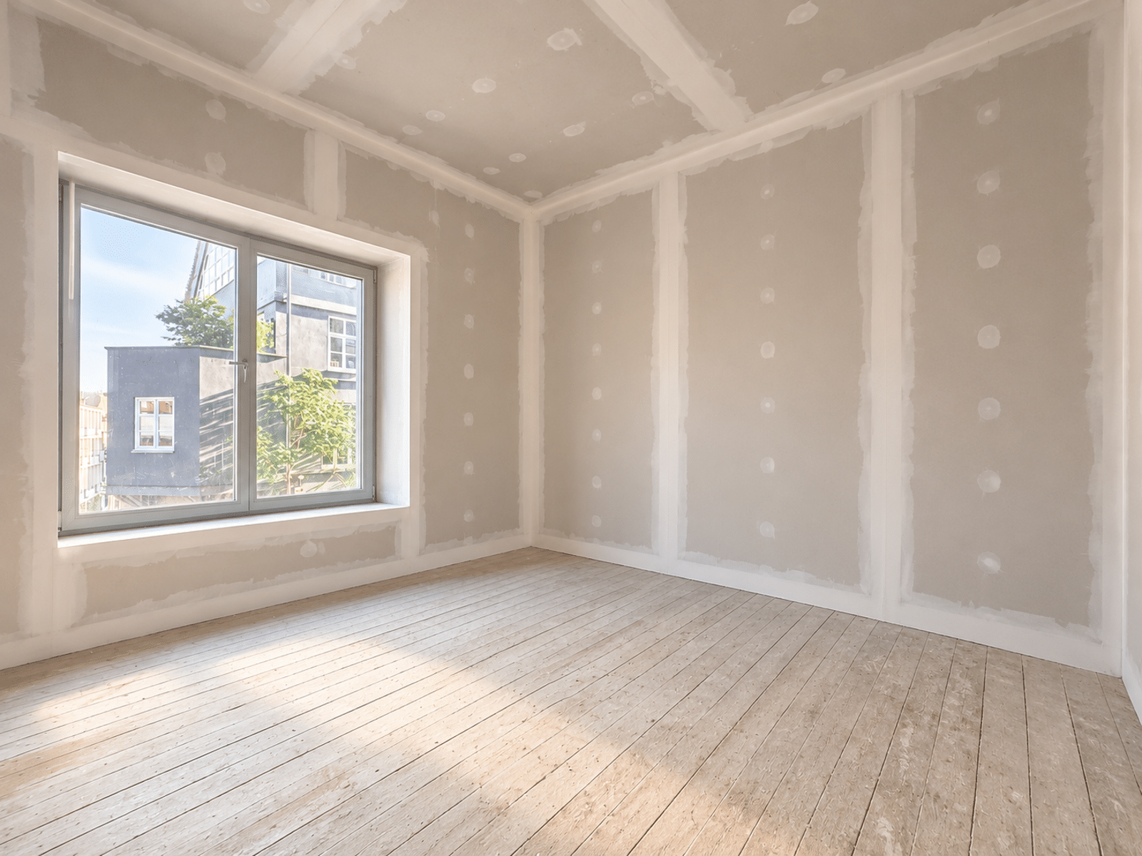 Lichtwoning in renovatie – You Real Estate Agency Lichte kamer in een appartement in renovatie, met houten parket en een groot raam.