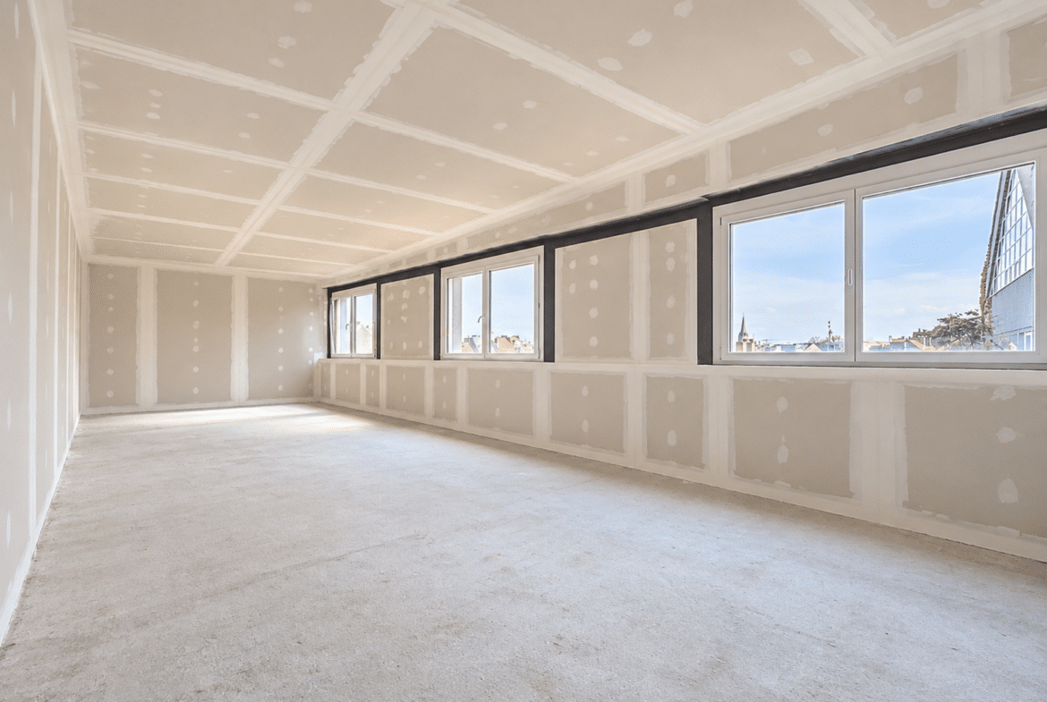 Groot appartement in renovatie met een ruime, lichte woonkamer en panoramische ramen.