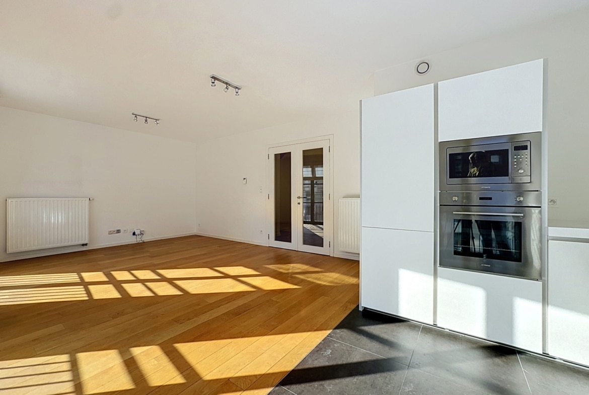 Licht appartement met open woonkamer, moderne inbouwkeuken en parketvloer.