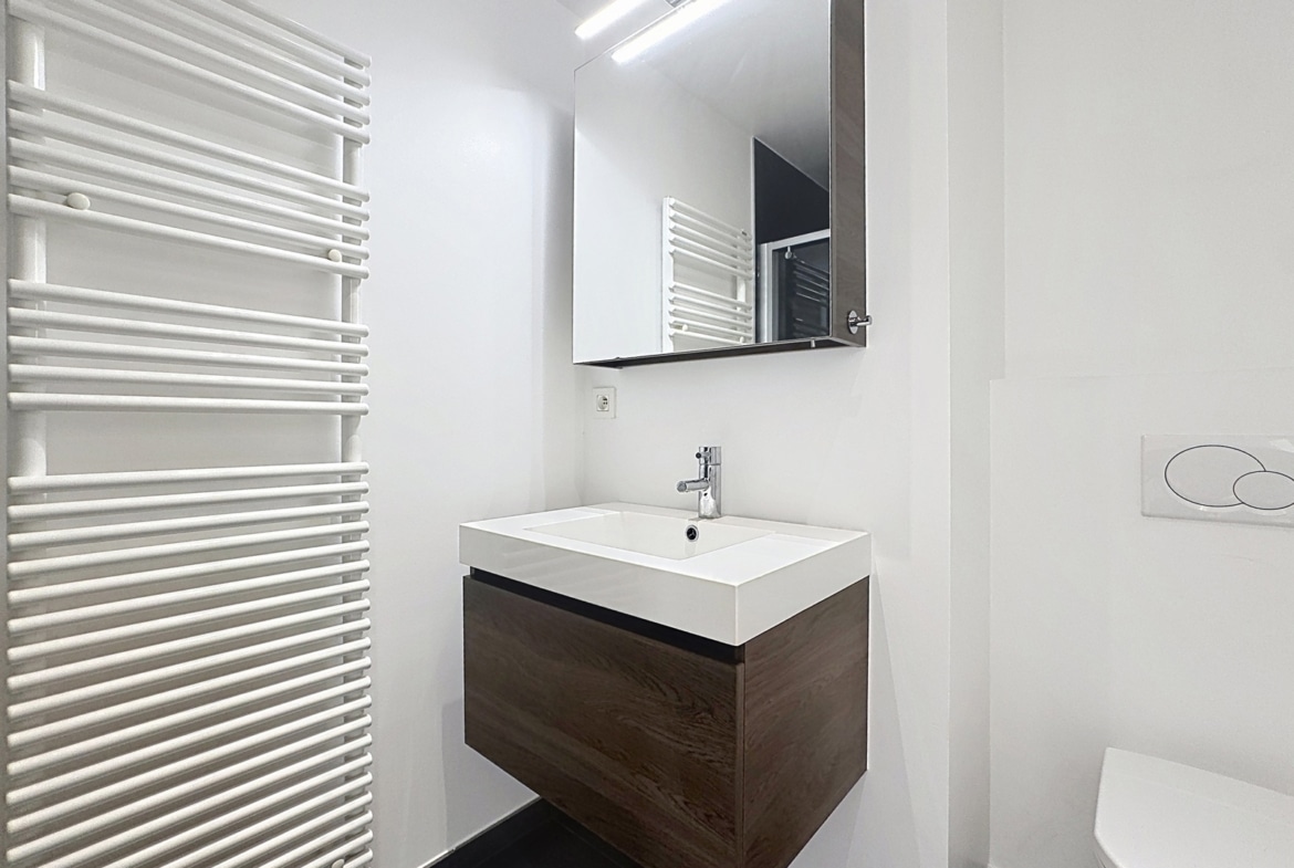 Moderne badkamer in een appartement met een hangende wastafelkast en een handdoekradiator.