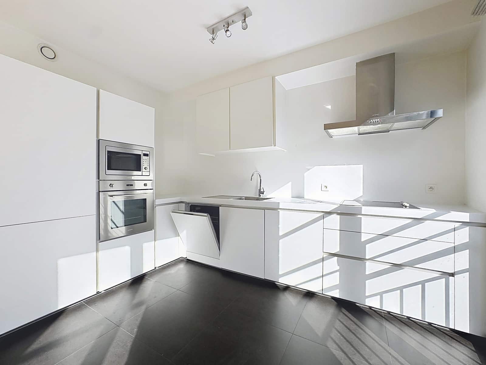 Moderne, goed uitgeruste en lichte keuken - You Real Estate Agency Lichte, moderne keuken met witte opbergruimtes en inbouwapparatuur in een nieuwbouwappartement.