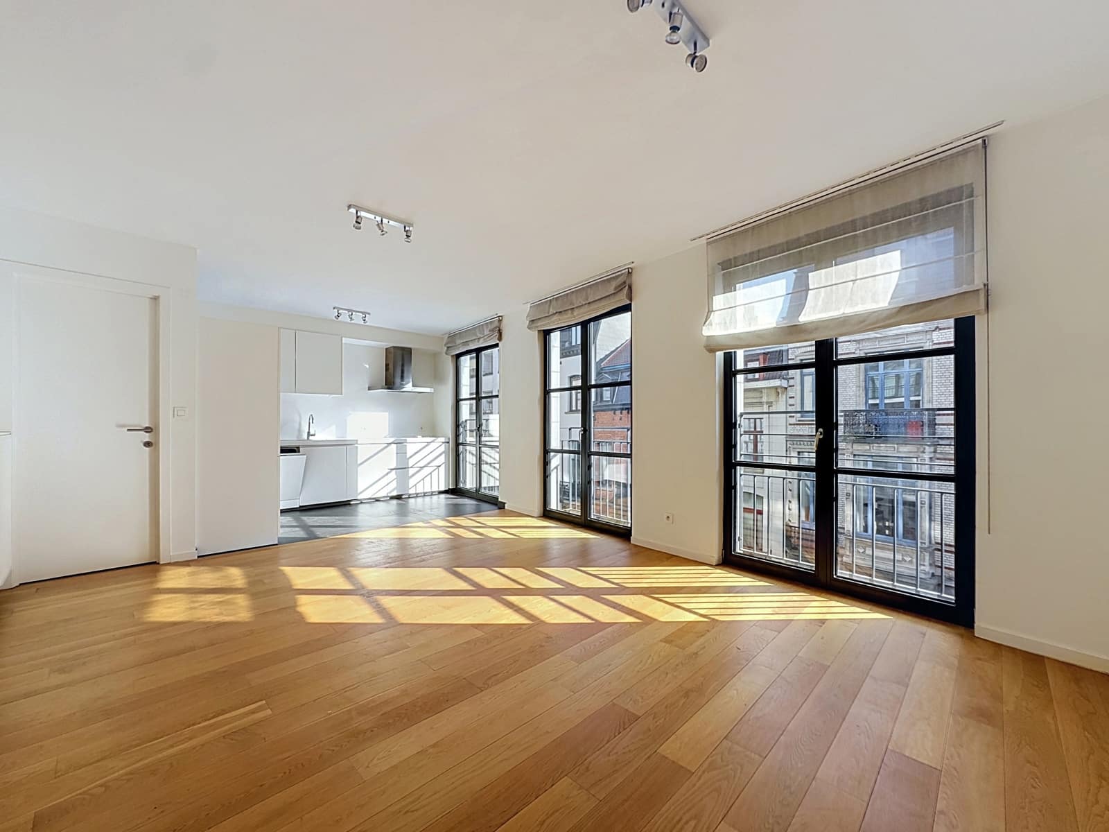 Lichte woonkamer met open keuken - You Real Estate Agency Lichte woonkamer met open keuken en balkon in een modern appartement.