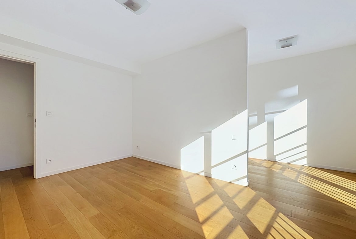 Lichte, lege woonkamer met houten parketvloer in een modern appartement.