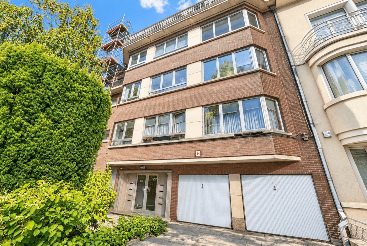 Immeuble résidentiel moderne avec appartements, garages et jardin arboré.