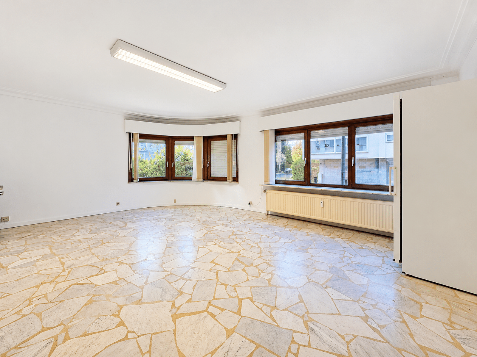 whise photo 16 Bright empty living room with curved bay windows and a beige mosaic tile floor, white walls.