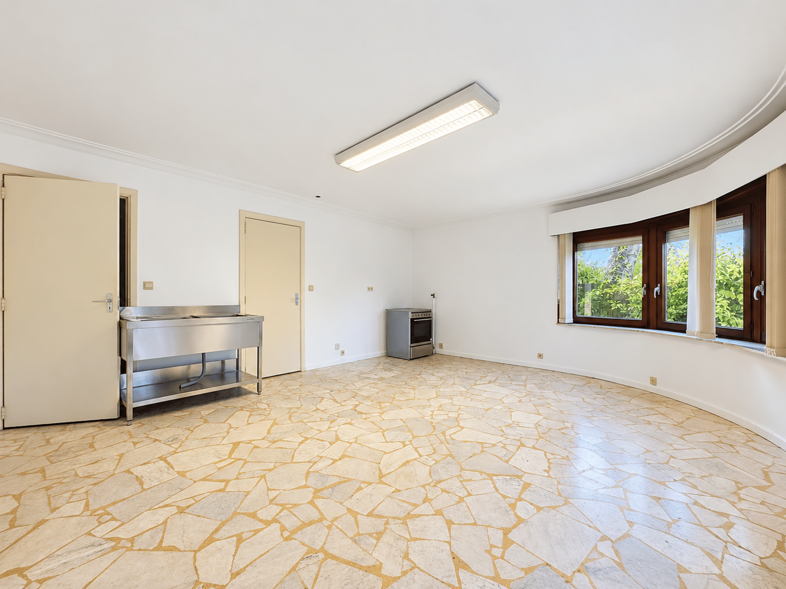 Pièce Lumineuse avec Baie Vitrée – You Real Estate Agency Grande pièce lumineuse avec coin cuisine et baie vitrée dans appartement à rénover.