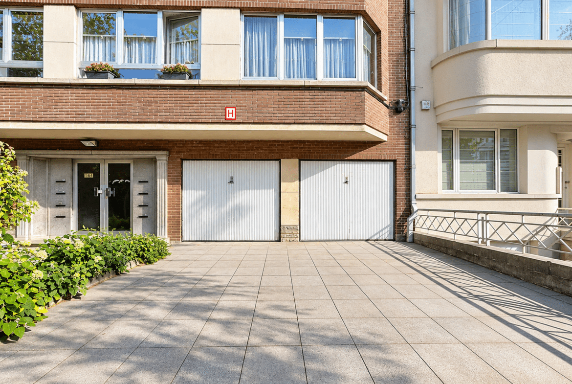 Façade en briques d’une maison avec garages et entrée pavée.