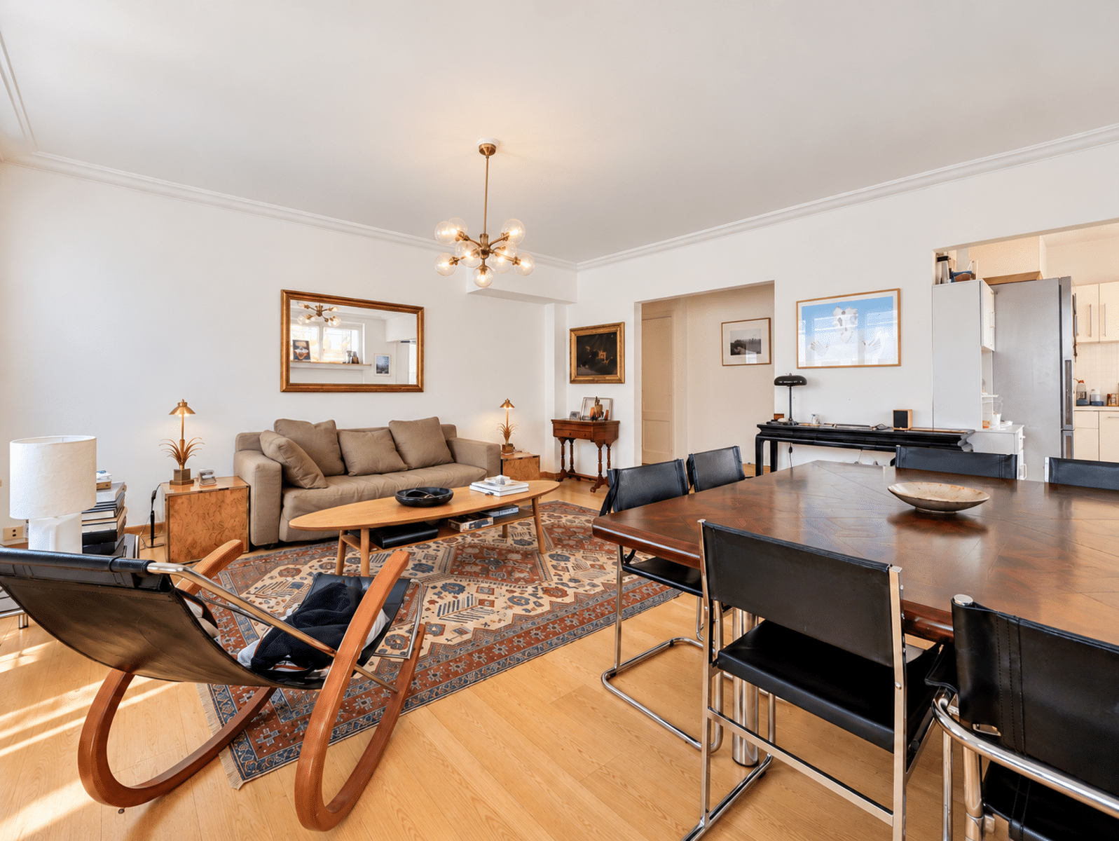 whise photo 4 Spacious living and dining room with a beige sofa, wooden coffee table, and a patterned rug under a modern chandelier.