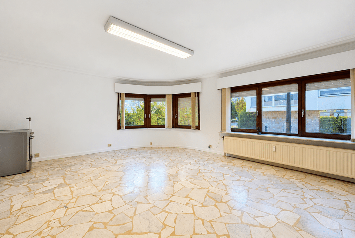 Salon lumineux d’appartement avec sol mosaïque et grandes fenêtres.