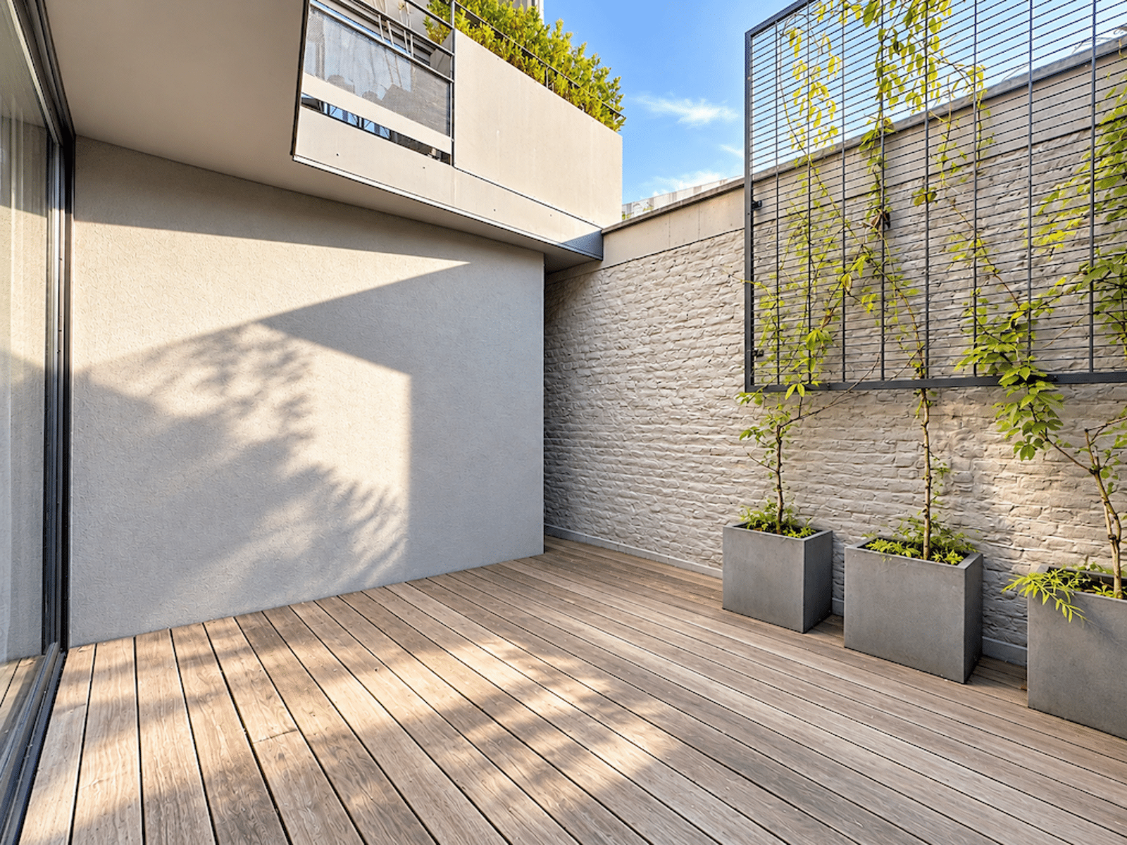 Terrasse Moderne En Bois – You Real Estate Agency Terrasse moderne en bois avec treillis végétalisé et baie vitrée d’appartement.