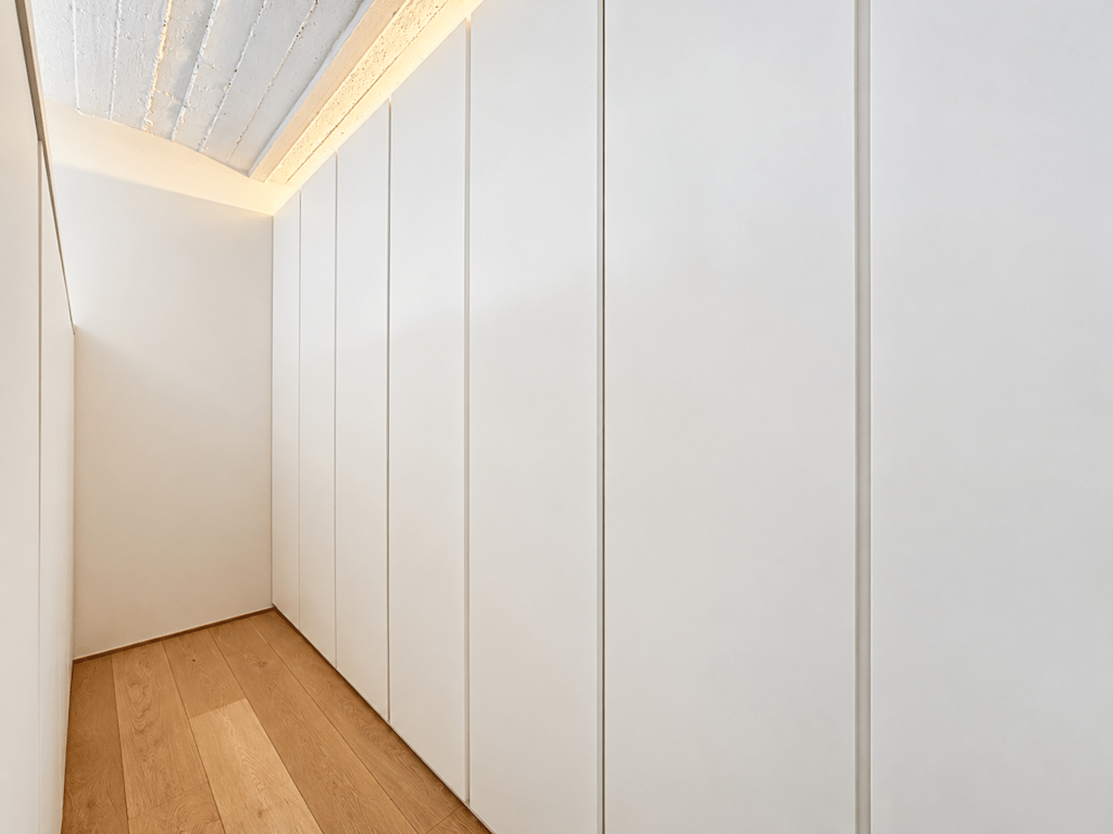 Dressing Moderne Intégré – You Real Estate Agency Dressing moderne avec rangements intégrés et parquet clair dans appartement contemporain.