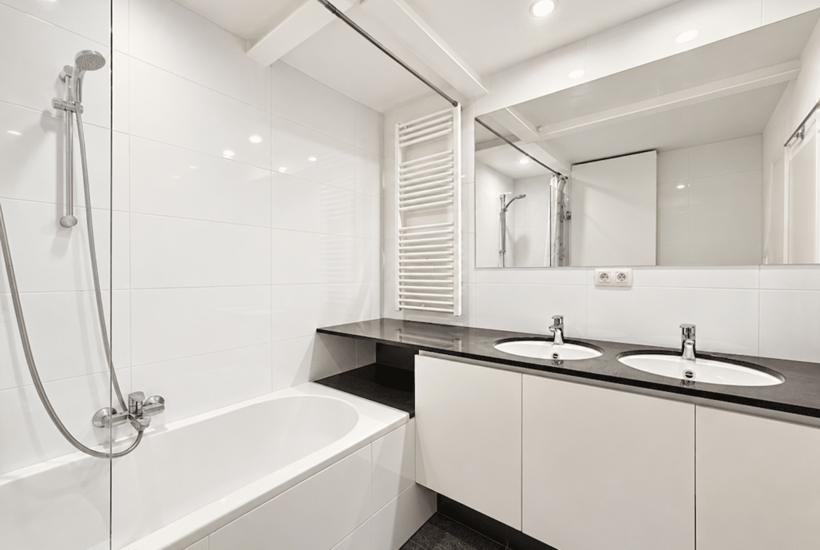 Salle de bain moderne avec double vasque et baignoire dans appartement lumineux.