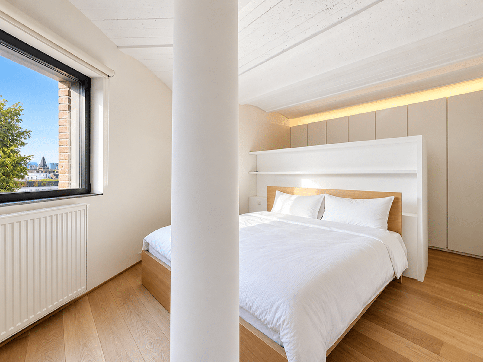 Chambre Moderne avec Grande Fenêtre – You Real Estate Agency Chambre lumineuse d’appartement moderne avec parquet, lit blanc et grande fenêtre.